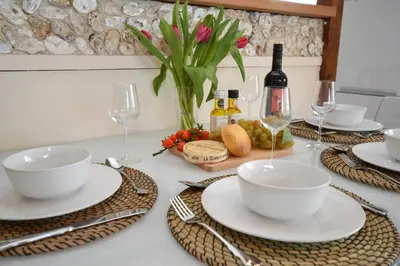 a table with plates and bowls and a vase of flowers at Clamshell Lodge in Otter Ferry