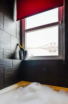 a bath tub in a bathroom with a window at Orocco Pier in Queensferry