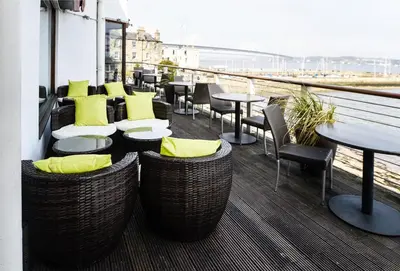 a restaurant with tables and chairs on a balcony at Orocco Pier in Queensferry