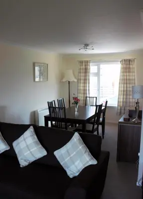 a living room with a couch and a dining room table at The Glebe, Am Fasgadh in Bowmore