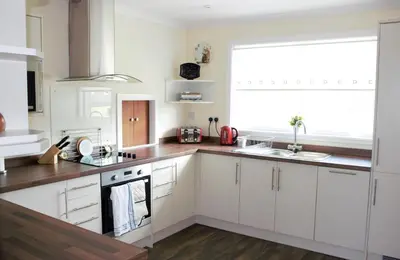 a kitchen with white cabinets and a large window at The Glebe, Am Fasgadh in Bowmore