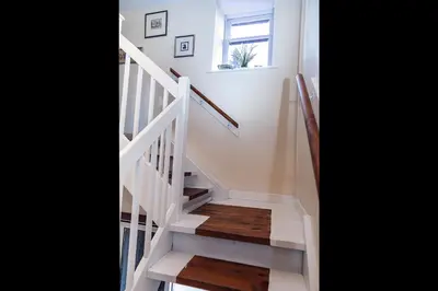 a white staircase with wooden floors and a window at Butler's Apartment. Flat 5, Dalmore House, Helensburgh, Scotland G84 8JP in Helensburgh