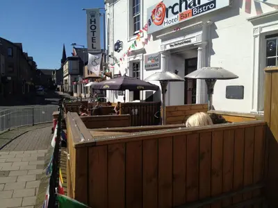 a restaurant with tables and umbrellas in front of a building at The Orchard Hotel in Falkirk