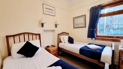 two beds in a small room with a window at The Guards Hotel in Edinburgh