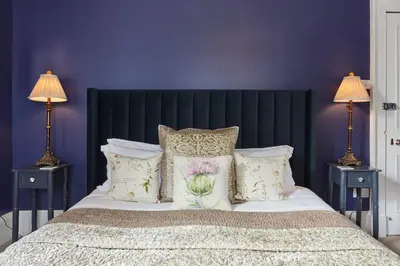 a bedroom with a large bed with purple walls at Merlindale in Crieff