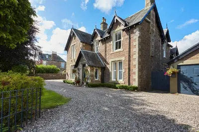 an old brick house with a gravel driveway at Merlindale in Crieff