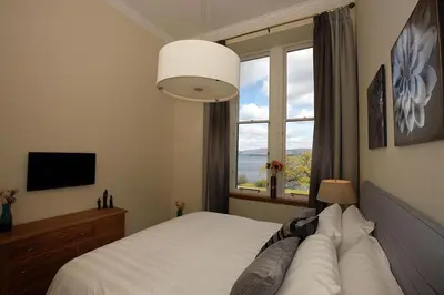 a bedroom with a white bed with a window at 4 Lomond Castle in Balloch