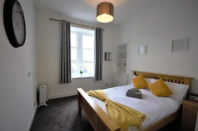 a bedroom with a bed with yellow pillows and a window at Bright and Cosy West End Apartment in Glasgow