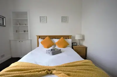 a bedroom with a bed with a yellow blanket on it at Bright and Cosy West End Apartment in Glasgow