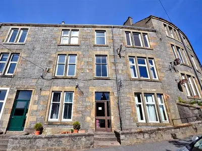 an old stone building with windows on a street at Apartment D 4 Battery Terrace Oban in Oban