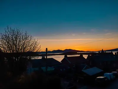 a sunset over a city with houses and a body of water at Apartment D 4 Battery Terrace Oban in Oban