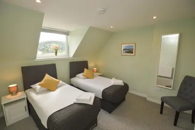 a room with two beds and a chair and a window at Fairhaven, Oban Town Centre in Oban