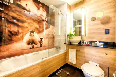 a bathroom with a bath tub with a picture of a sheep at Leonardo Hotel Edinburgh Haymarket in Edinburgh