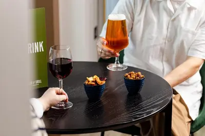 two people sitting at a table with two glasses of wine and snacks at Leonardo Hotel Edinburgh Haymarket in Edinburgh