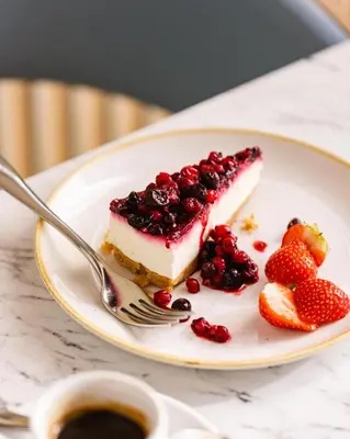 a piece of cake with berries on a plate with a fork at Leonardo Hotel Edinburgh Haymarket in Edinburgh