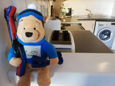 a stuffed teddy bear holding two baseball bats on a counter at Stylish Merchant City Flat in Glasgow