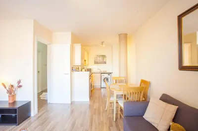 a living room with a couch and a table and a kitchen at Stylish Merchant City Flat in Glasgow