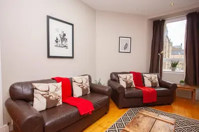 a living room with a couch and a chair at Beautiful 2 Bed Apartment Rose St in Glasgow