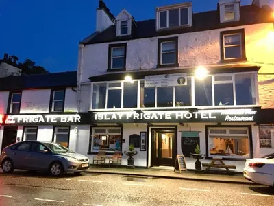a building with a car parked in front of it at Islay Frigate Hotel in Tarbert