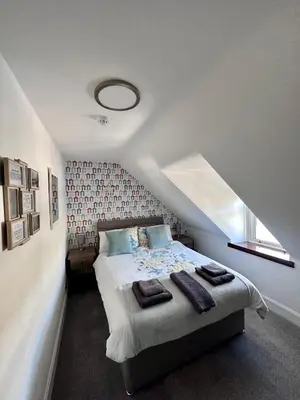 a bedroom with a bed with a red wall at Islay Frigate Hotel in Tarbert