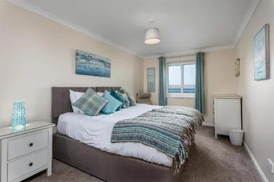 a bedroom with a large bed and a window at Arran View - Coorie Doon Stays in Ayr