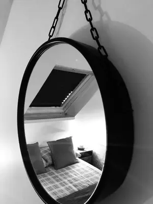 a mirror hanging on a wall next to a bed at Fisher Holiday Cottage Ayrshire in Girvan
