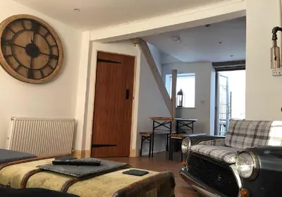 a living room with a clock on the wall and a couch at Fisher Holiday Cottage Ayrshire in Girvan