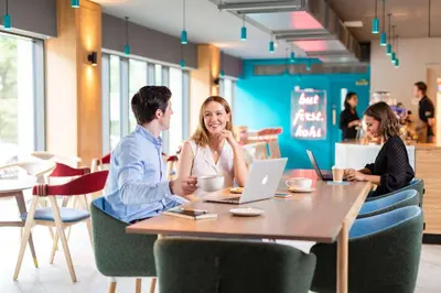 a group of people sitting at a table with a laptop at YOTEL Edinburgh in Edinburgh