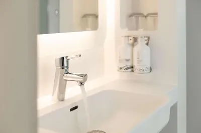 a white bathroom with a sink and a faucet at YOTEL Edinburgh in Edinburgh