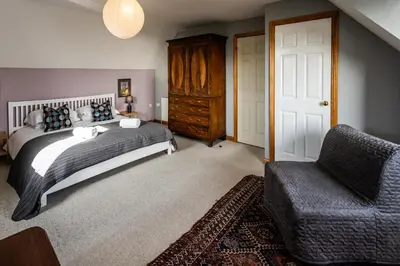 a bedroom with a bed and a chair at Shorefield, Bruichladdich in Bruichladdich