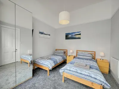 two beds in a room with glass walls at Hayfield Apartment in Oban