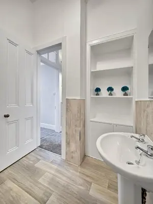 a white bathroom with a sink and a mirror at Hayfield Apartment in Oban