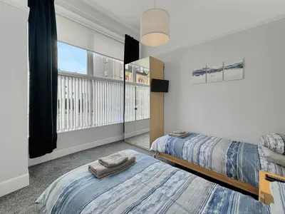 a bedroom with two beds and a large window at Hayfield Apartment in Oban