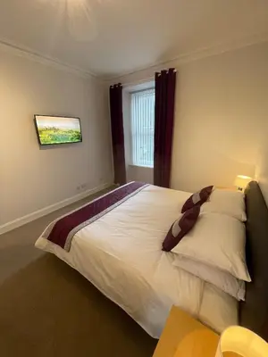 a bedroom with a large white bed with a window at Apartment 39c in Oban