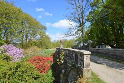 a stone wall next to a garden with flowers at Rhoda`s Cottage in Creggans
