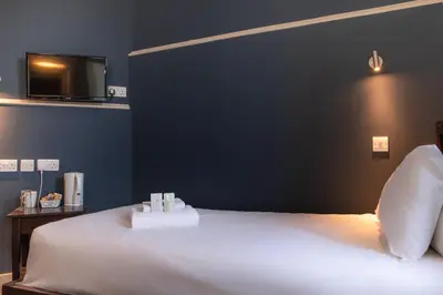 a bedroom with a white bed with a tv on the wall at JOIVY Haymarket in Edinburgh