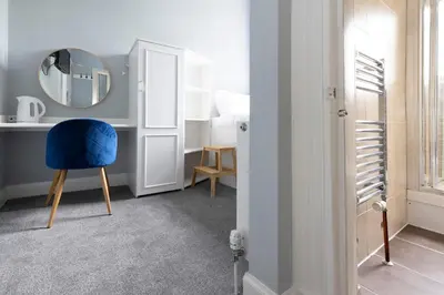 a room with a blue chair and a mirror at JOIVY Haymarket in Edinburgh