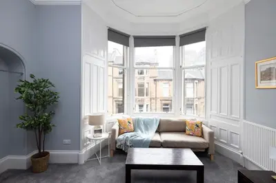 a living room with a couch and a large window at JOIVY Haymarket in Edinburgh