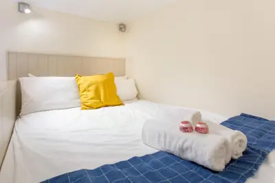 a white bed with a yellow pillow and two towels at JOIVY Haymarket in Edinburgh