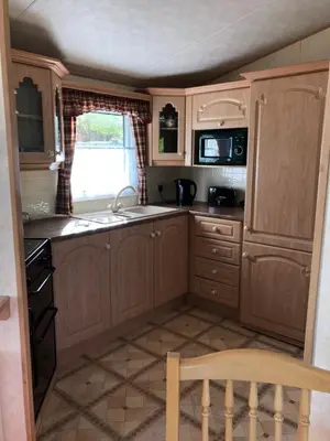 a small kitchen with wooden cabinets and a sink at Lyndhurst 28 in Dunoon