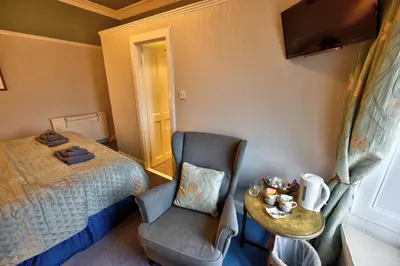 a bedroom with a bed and a chair and a table at Burnside Guest House in Ayr