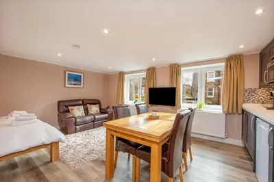 a living room with a dining room table and a kitchen at Mandarin Premier Apartments C - studio apt in Oban