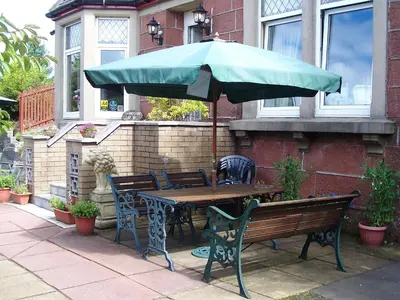 a wooden table and bench with an umbrella at Sunnyside B&B in Balloch