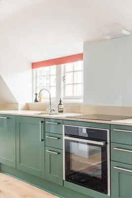 a kitchen with green cabinets and an oven at Amazing penthouse, stunning views, Castle 2 mins in Edinburgh