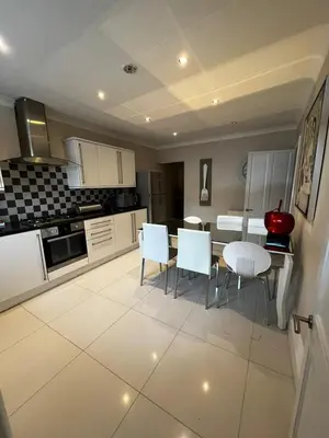 a kitchen with white cabinets and a table and chairs at WEST END -Stunning, 2 bedroom, main door flat with private parking in Glasgow