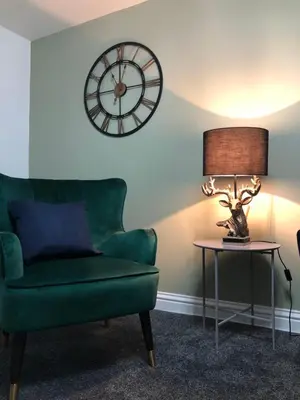 a living room with a green couch and a clock at The Nook - Coorie Doon in Ayr