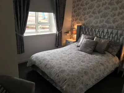 a bedroom with a bed with pillows and a window at The Nook - Coorie Doon in Ayr