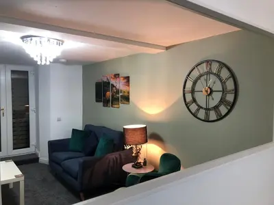 a living room with a couch and a clock on the wall at The Nook - Coorie Doon in Ayr