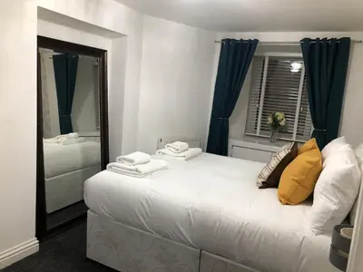 a bedroom with a large white bed and a mirror at The Nook - Coorie Doon in Ayr