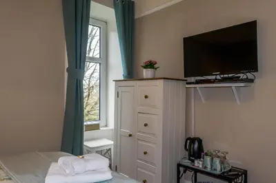 a bedroom with a bed with a television and a dresser at The Tregortha B&B in Tighnabruaich